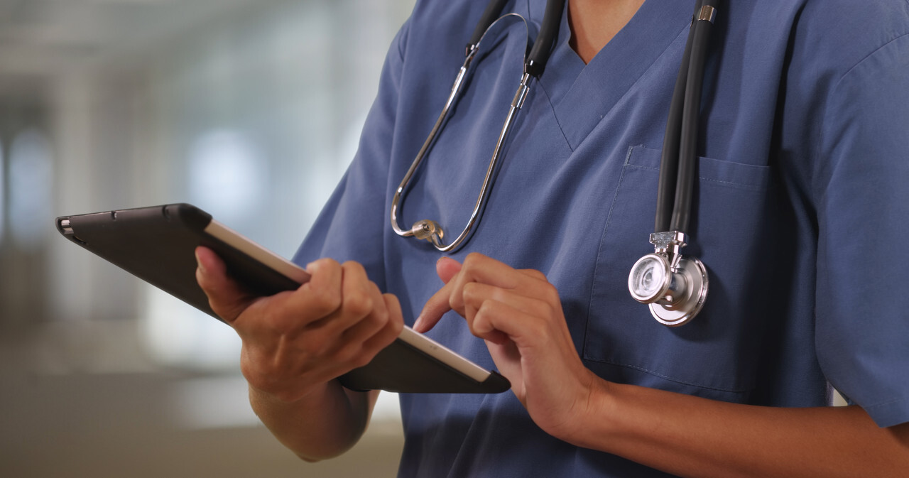 Close up of woman nurse or doctor working on tablet computer inside hospital